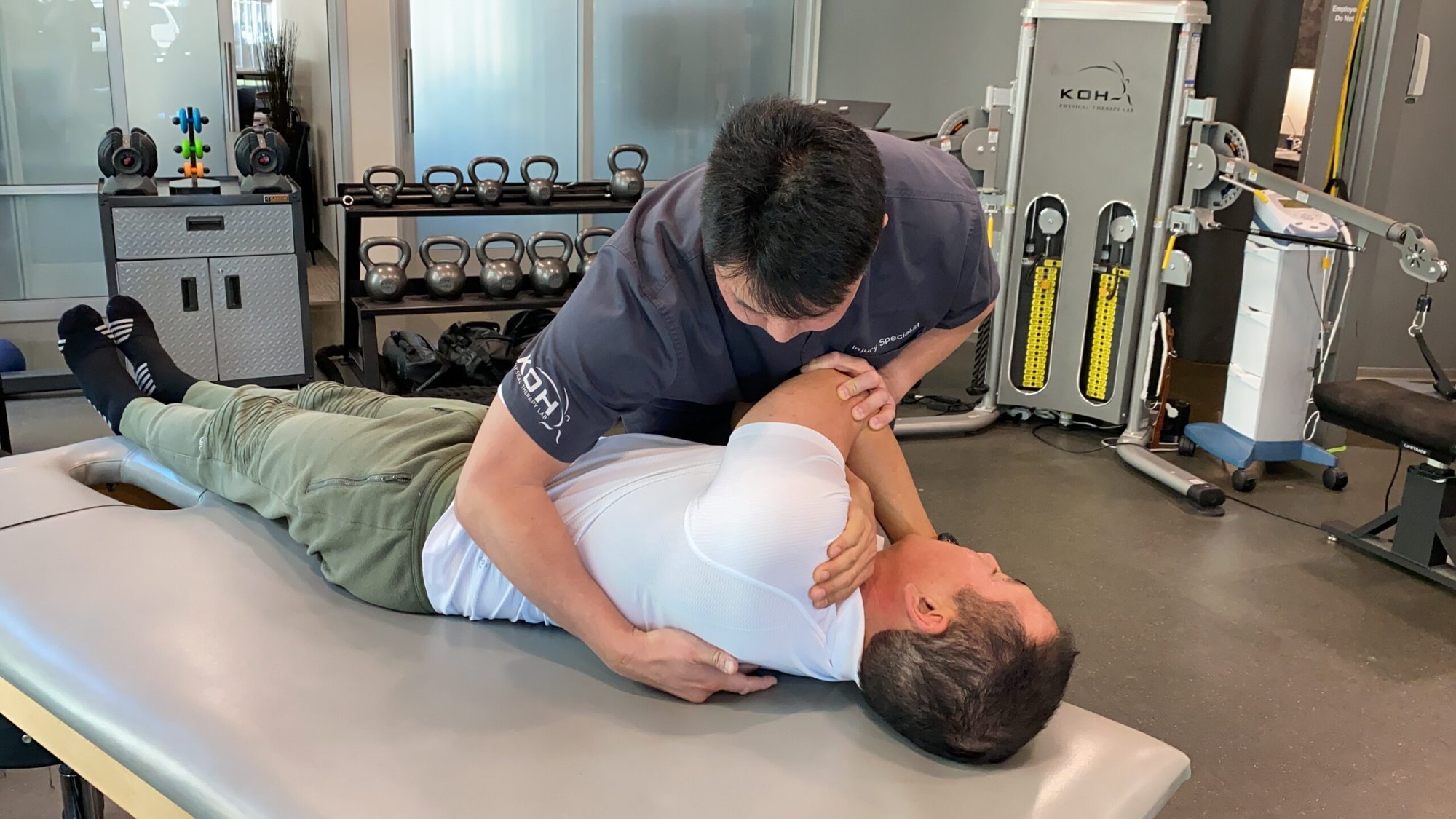 Dr. Koh performing a manual therapy technique on a client lying on a treatment table